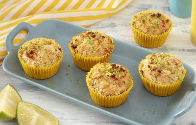 Foto da receita de Muffin de Limão. Observa-se uma bandeja de porcelana azul claro com 4 muffins em forminhas amarelas em cima, polvilhados com limão e NINHO em Pó.