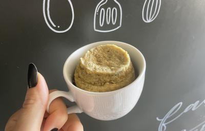 Imagem da Receita de Bolo de Caneca de Banana sem Açúcar, em uma caneca branca e ao fundo uma lousa