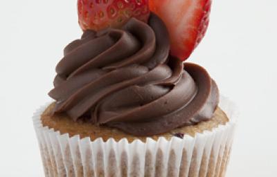 um bolinho com cobertura de chocolate por cima e frutas vermelhas para decorar