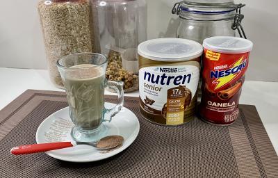 Imagem da receita de Cappuccino Proteico, sobre uma mesa, ao lado uma lata de Nutren Protein e Nescau Canela