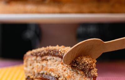 Foto da receita de Pavê Delícia. Observa-se uma fatia do pavê sendo cortado por uma colher de madeira.