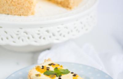 fotografia em tons de branco e amarelo tirada de uma torta com uma fatia retirada, à frente um prato redondo com a fatia de torta e um garfo para servir.