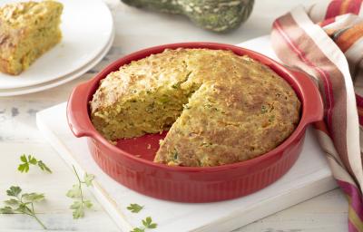 Foto da receita de Torta de Casca de Abóbora com Recheio de Talos. Observa-se a torta assada dentro de um recipiente refratário vermelho com um pedaço cortado