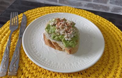 Imagem da receita de Avocado Toast, em um prato branco, sobre uma mesa e ao lado os talheres