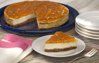 fotografia em tons de cinza, branco e azul de uma bancada cinza vista de frente. Contém um prato redondo e branco com uma fatia de torta ao fundo um prato redondo azul com a torta faltando uma fatia. Ao lado pratos brancos e um pano branco com rosa.