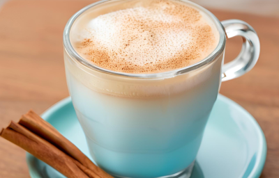 Foto da receita de Café Gelado Proteico. Observa-se uma xícara de vidro com a bebida dentro, polvilhada de canela. Foto gerada por IA.