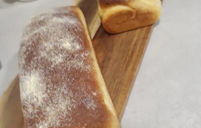 Fotografia de dois pães grandes de milho sobre uma tábua retangular de madeira.