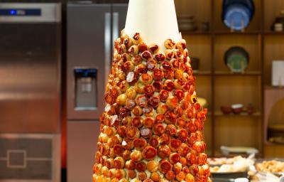 Fotografia em tons de caramelo com uma torre de choux com creme de confeiteiro com toque de laranja.