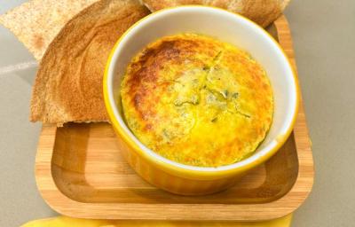 Fotografia em tons de amarelo com um ramekin amarelo ao centro. Dentro dele existe uma receita de ovos cremosos acompanhado de pão.