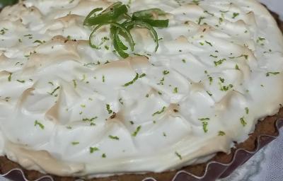 Foto da receita de Torta de Limão. Observa-se uma Torta de Limão grande e inteira com merengue queimadinho e raspas de limão por cima decorando