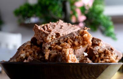 Fotografia de alguns docinhos com cobertura de Chocolate ao Leite GAROTO com crespinho de arroz dentro de um recipiente preto fundo.