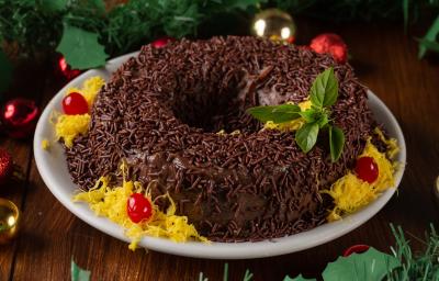 Receita de Brigadeirão de Natal, tradicional e delicioso, feito com Leite MOÇA, NESTLÉ Creme de Leite, Chocolate em Pó NESTLÉ CHOCOLATERIA, açúcar, ovos e margarina, decorado com fios de ovos, cerejas e sobre uma mesa de natal