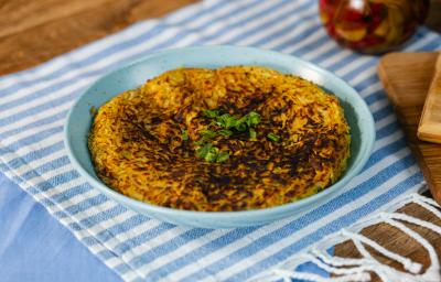 Fotografia em tons de azul com um prato azul ao centro. Em cima do prato existe uma receita de batata-doce rosti recheada com carne desfiada