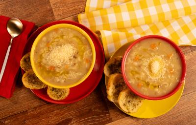 Fotografia mostra duas cumbucas com sopa de carne com legumes e queijo povilhado sobre um prato. Ao lado, torradas temperadas.