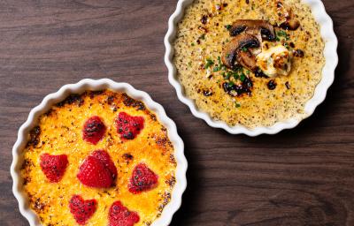 Fotografia vista de cima de dois ramekins de cremes brulée, um de cogumelo com gorgonzola e o outro de baunilha com framboesa. As sobremesas estão sobre uma mesa de madeira.