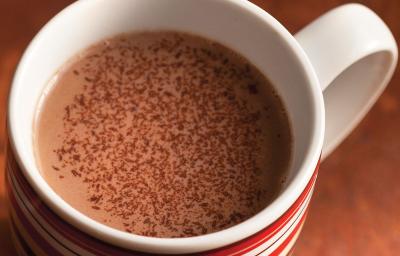 fotografia em tons de marrom e branco tirada de cima, contém uma xicara com chocolate quente.