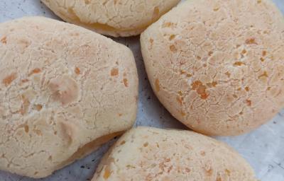 Fotografia de quatro pães de queijo sobre uma forma de alumínio.