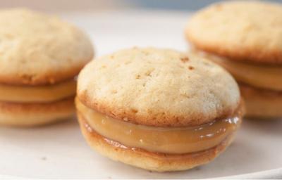 3 Whoopie de Banana com recheio de Doce de Leite por cima de um prato redondo e branco.