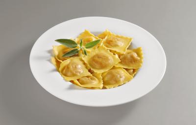 Foto da receita de Tortelli. Observa-se um prato repleto de tortellis com sálvia em um prato branco redondo.