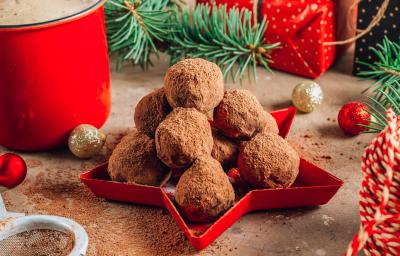 Fotografia mostra uma bandeja vermelha com trufas de chocolate perfeitas, cobertas com uma camada de chocolate em pó aveludado.