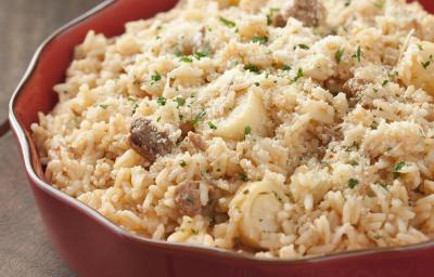 fotografia em tons de cinza e vermelho de uma bancada cinza vista de cima. Contém um recipiente vermelho redondo com o risoto e ao lado um pano vermelho