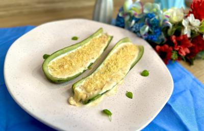 Fotografia em tons de azul com um prato branco com centro. Dentro do prato existe uma receita de abobrinha recheada com creme de ASCENDA e cream cheese