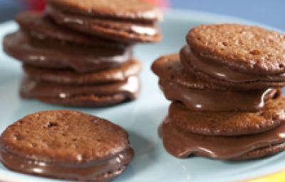 fotografia em tons de marrom, branco e azul tirada de uma bailarina branca com Whoopies Nescau por cima com recheio de brigadeiro