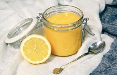 Foto da receita de Lemon Curd. Observa-se um potinho de vidro hermético com o creme de limão dentro e, ao lado esquerdo, um limão pela metade decora a foto.