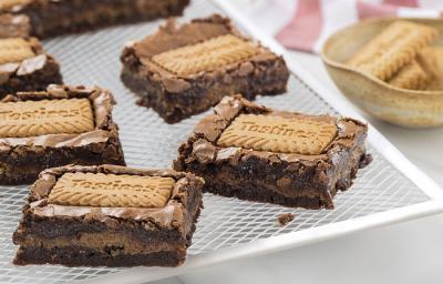 Foto da receita de Brownie de Tostines. Observa-se 5 fatias de brownie com o Biscoito TOSTINES Especiarias em cima e recheado de creme.