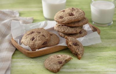 Foto da receita de Cookie Vegano. Observa-se 7 cookies dispostos em uma tábua de madeira, sendo que um está cortado ao meio.