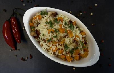 Foto vista de cima da receita de Arroz com Bacon e Cenoura, servido em um refratário de vidro branco, em uma bancada decorada com duas pimentas dedo-de-moça