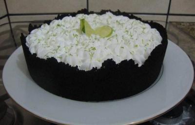 Foto da receita de Torta de Limão com Biscoito. Observa-se uma torta com base escura de chocolate em um prato branco.