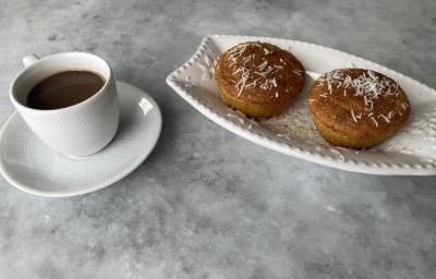 Imagem da receita de Muffin de Milho sem Glúten, em um recipiente branco e ao lado uma xícara de café