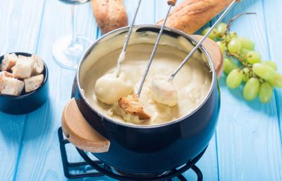 Foto da Receita de Fondue de Queijo Sem Lactose. Observa-se uma panelinha de fondue azul com três espátulas de pão dentro.