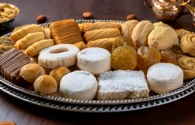 sobre uma mesa de madeira, uma bandeja de prata repleta de doces amanteigados e petit fours em diferentes formatos. Eles são pequenos, dourados, alguns com açúcar, outros com chocolate. sobre uma mesa de madeira, uma bandeja de prata repleta de doces amanteigados e petit fours em diferentes formatos. Eles são pequenos, dourados, alguns com açúcar, outros com chocolate.