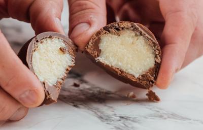 Foto da receita de Bombom de Prestígio. Observa-se uma foto bem perto do bombom cortado ao meio, expondo o recheio cremoso de coco.