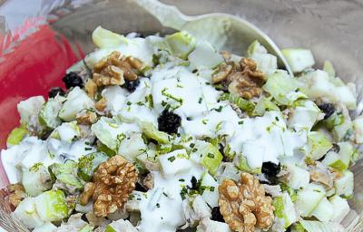 fotografia tirada de cima, contém um pano vermelho e um recipiente redondo de vidro transparente com a salada dentro e creme