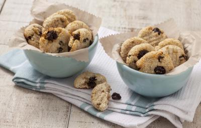 Fotografia em tons de branco e azul de uma bancada branca com um paninho azul e branco, sobre ele dois recipiente redondos azuis com biscoitinhos.