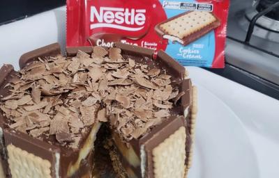 Fotografia de uma torta duo com chocotrio de cookies'n cream com raspas de nestlé classic. A torta está sobre um apoio branco.