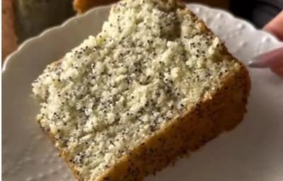 Fotografia de uma fatia grande de bolo de chia com limão sobre um prato branco.