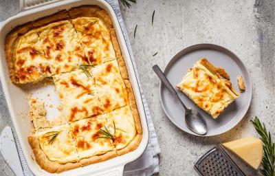 Fotografia mostra uma torta salgada coberta com uma superfície dourada e decorada com ervas frescas.