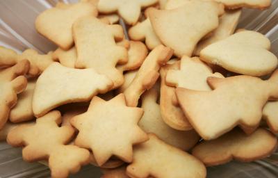 Fotografia em tons de caramelo com vários biscoitos amanteigados ao centro. Cada biscoitinho tem um formato diferente.