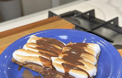 Fotografia de uma receita de smores com cookie em um prato de vidro raso sobre uma tábau de madeira. Fotografia de uma receita de smores com cookie em um prato de vidro raso sobre uma tábau de madeira.
