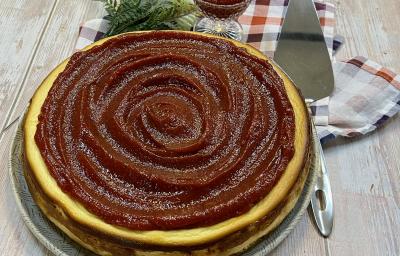 Foto da Receita de Torta de Ricota com Goiabada. Observa-se uma torta inteira com uma espátula prateada ao lado direito em cima de uma tábua de madeira clara.