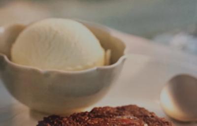 Foto da receita de Bolo Quente com Geleia da consumidora Caroline Lima. Observa-se um bolo baixo de chocolate com calda brilhosa por cima e, atrás, em um pote de cerâmica, uma bola de sorvete de creme.