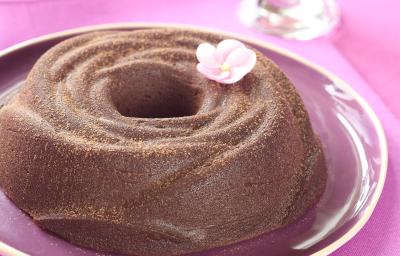 Fotografia de um brigadeirão sobre um prato rosa, decorado com uma flor rosa.