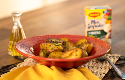 Foto da Receita de Batata Bolinha Sautée. Observa-se um prato vermelho com as batatinhas. Do lado esquerdo, um pote transparente com azeite e, do direito, um garfo e uma embalagem de Maggi Meu Segredo 7 Vegetais.