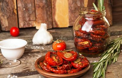 Fotografia em tons de marrom com um pote de vidro ao centro. Dentro do pote existe uma receita de tomate seco feita na Air Fryer