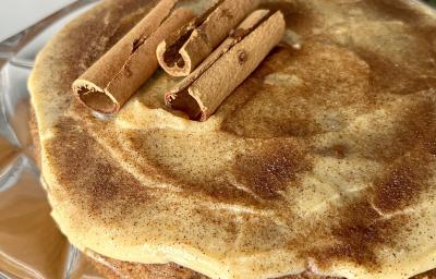 Fotografia mostra um bolo com cobertura de creme claro, polvilhado com canela. Fotografia mostra um bolo com cobertura de creme claro, polvilhado com canela.