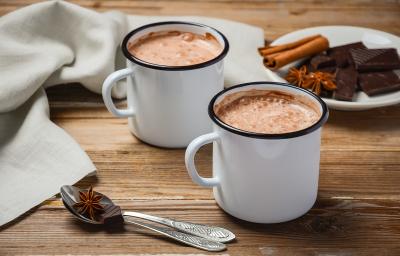 fotografia em tons de branco e marrom tirada de duas xicaras brancas com chocolate quente dentro